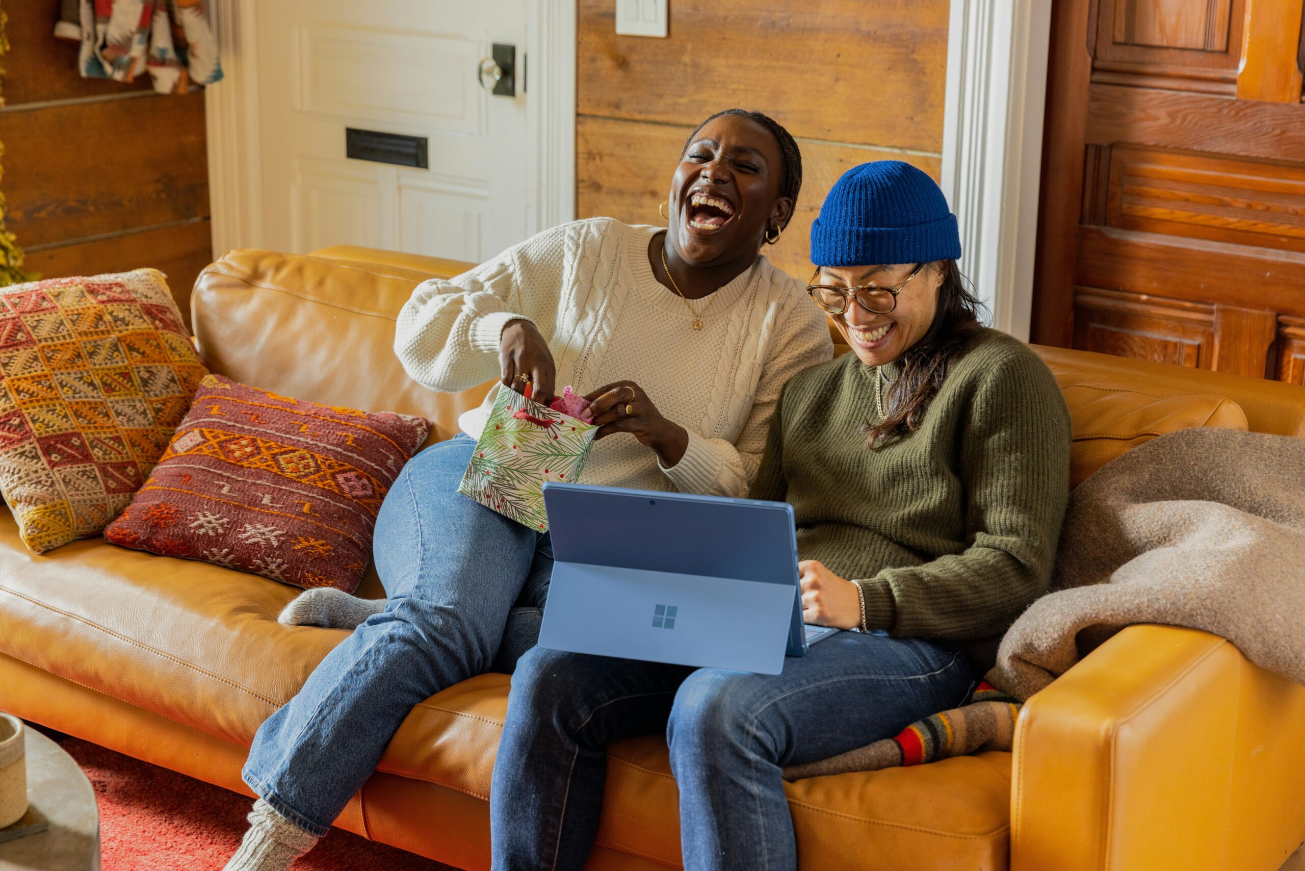 Two female friends sitting on a couch and laughing
